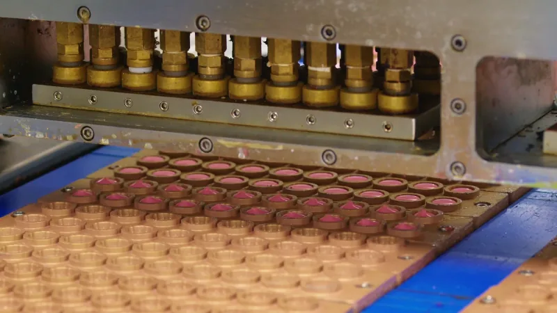 Brass mold plates being filled with gummy slurry on the depositing line